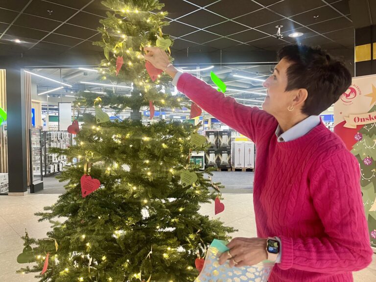 Grethe Uddal fyller på røde hjerter med julegaveønsker og samtidig henger opp grønne for de ønskene som er oppfylt. (Foto: A. S. Trandal)